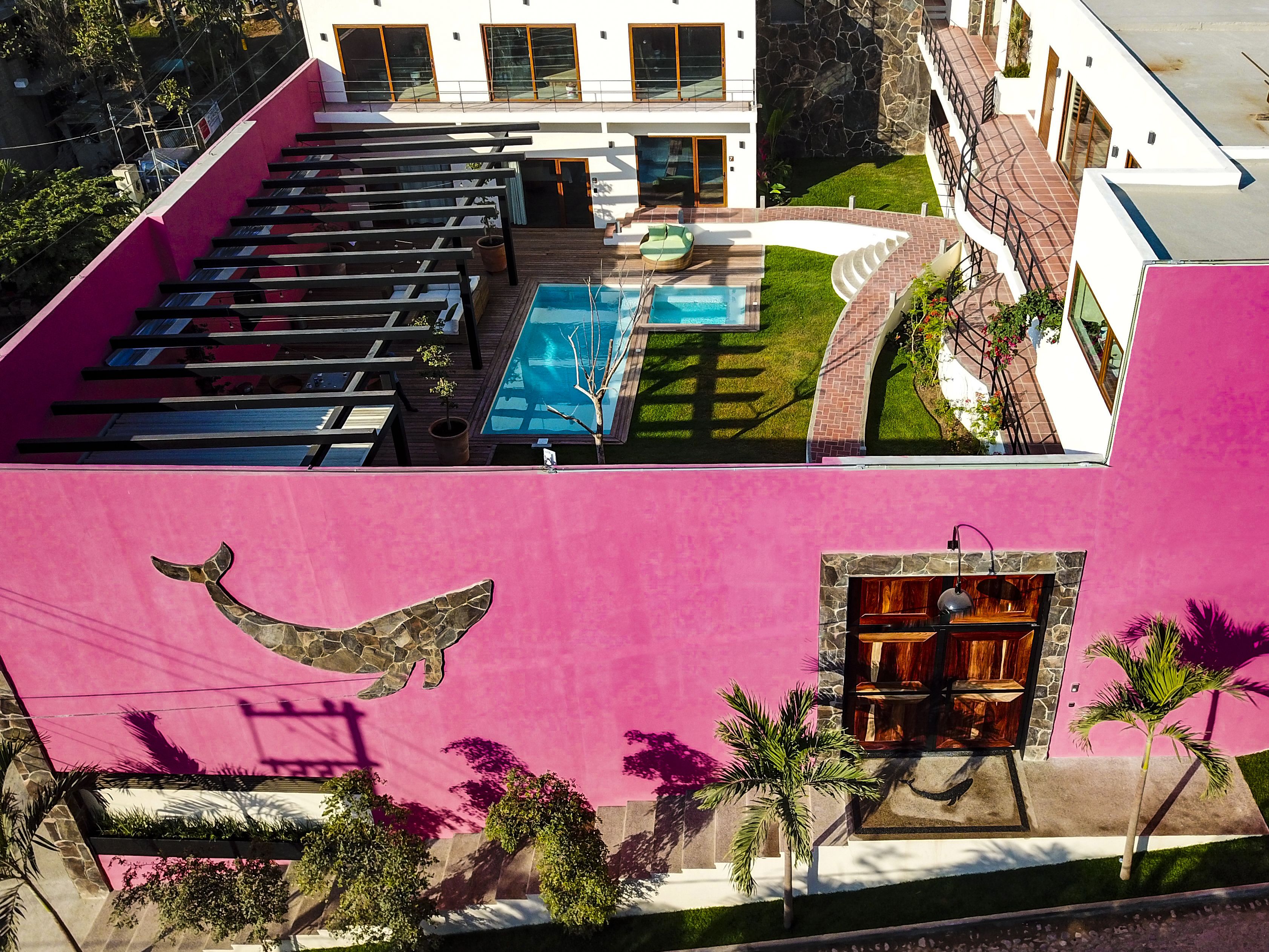 Un edificio moderno con piscina en la azotea, chimenea de piedra y un mural de un ave.