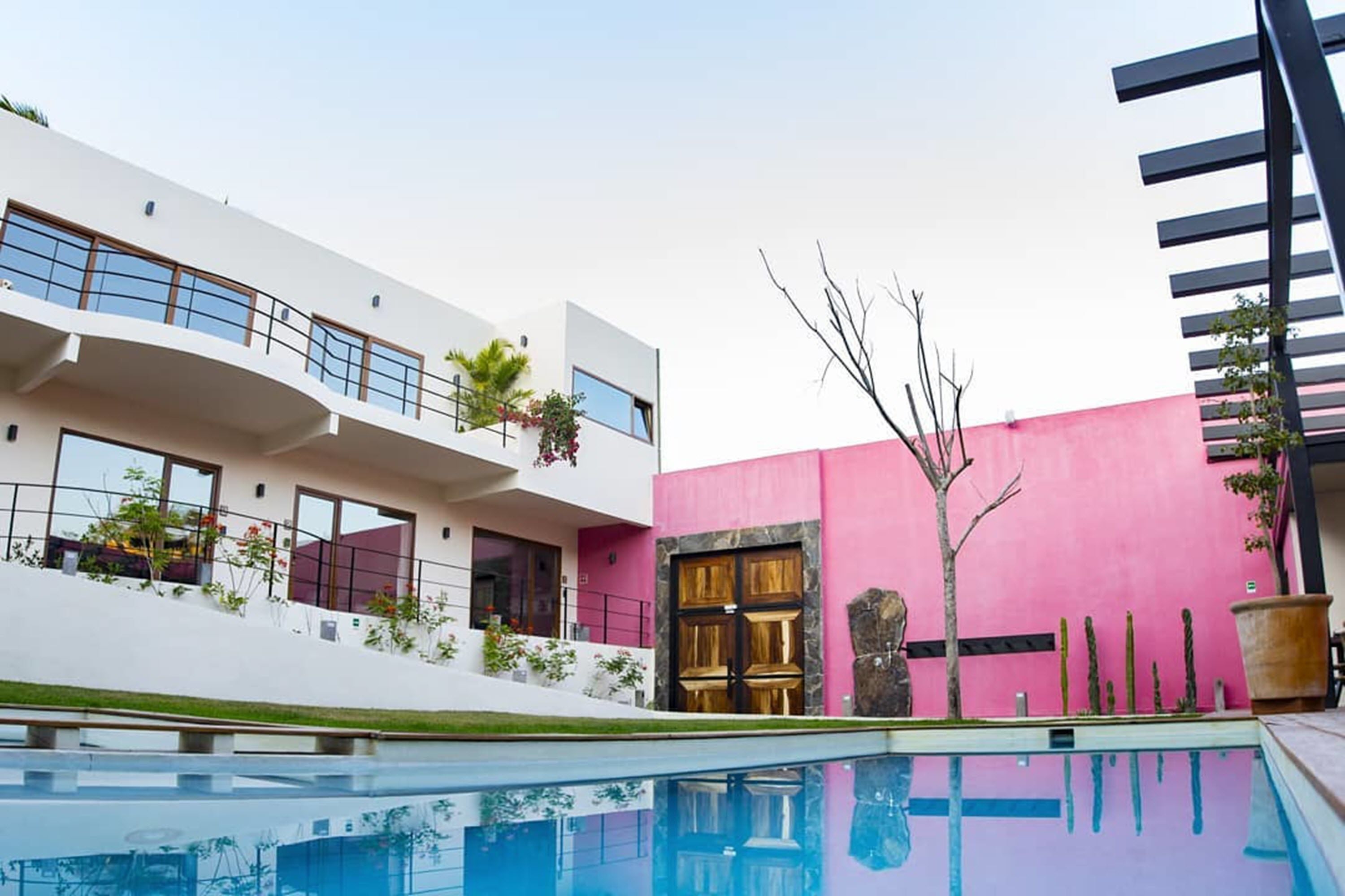 A modern building with a pool, balconies, and a pink wall.