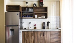 A modern kitchen with a stainless steel refrigerator, wooden cabinets, and a countertop with various kitchen items. - Casa de la Ballena (Sayulita)