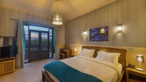 Een hotelkamer met een groot bed, een televisie, een bureau en een balkon met uitzicht.