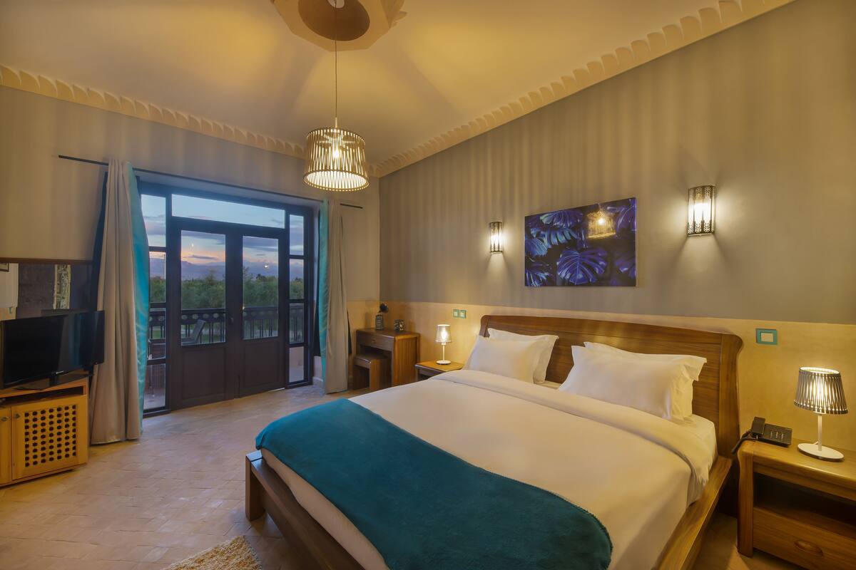 Une chambre d’hôtel avec un grand lit, une télévision, un bureau et un balcon avec vue.