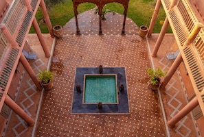 A rooftop pool area with a tiled floor, surrounded by columns, and potted plants. - Le Chant des Oliviers Marrakesh (Marrakech)