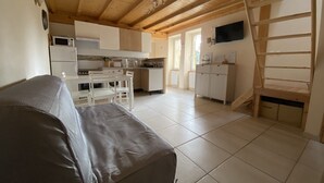 A cozy living area with a sofa, a kitchen with white cabinets, and a wooden ceiling. - Gîte Le Papillon - Le Cocon de Curson (Chanos-Curson)