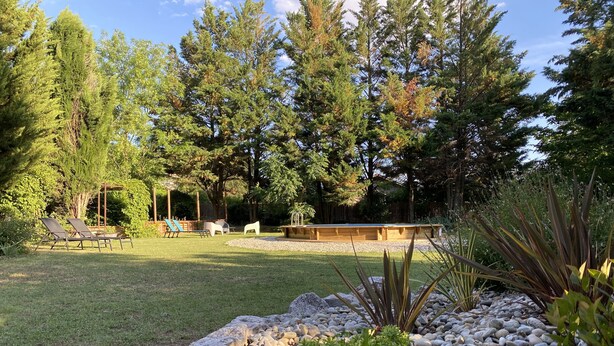 A backyard with a lawn, a wooden deck, and a rock garden. - Gîte Le Papillon - Le Cocon de Curson (Chanos-Curson)