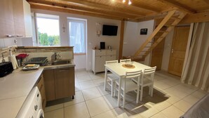 A kitchen with a dishwasher, sink, and a dining area with a table and chairs. There is a staircase leading to another level. - Gîte Le Papillon - Le Cocon de Curson (Chanos-Curson)