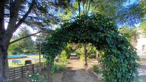 A garden pathway leading to a pool area with a wooden fence and outdoor seating. - Gîte Le Papillon - Le Cocon de Curson (Chanos-Curson)