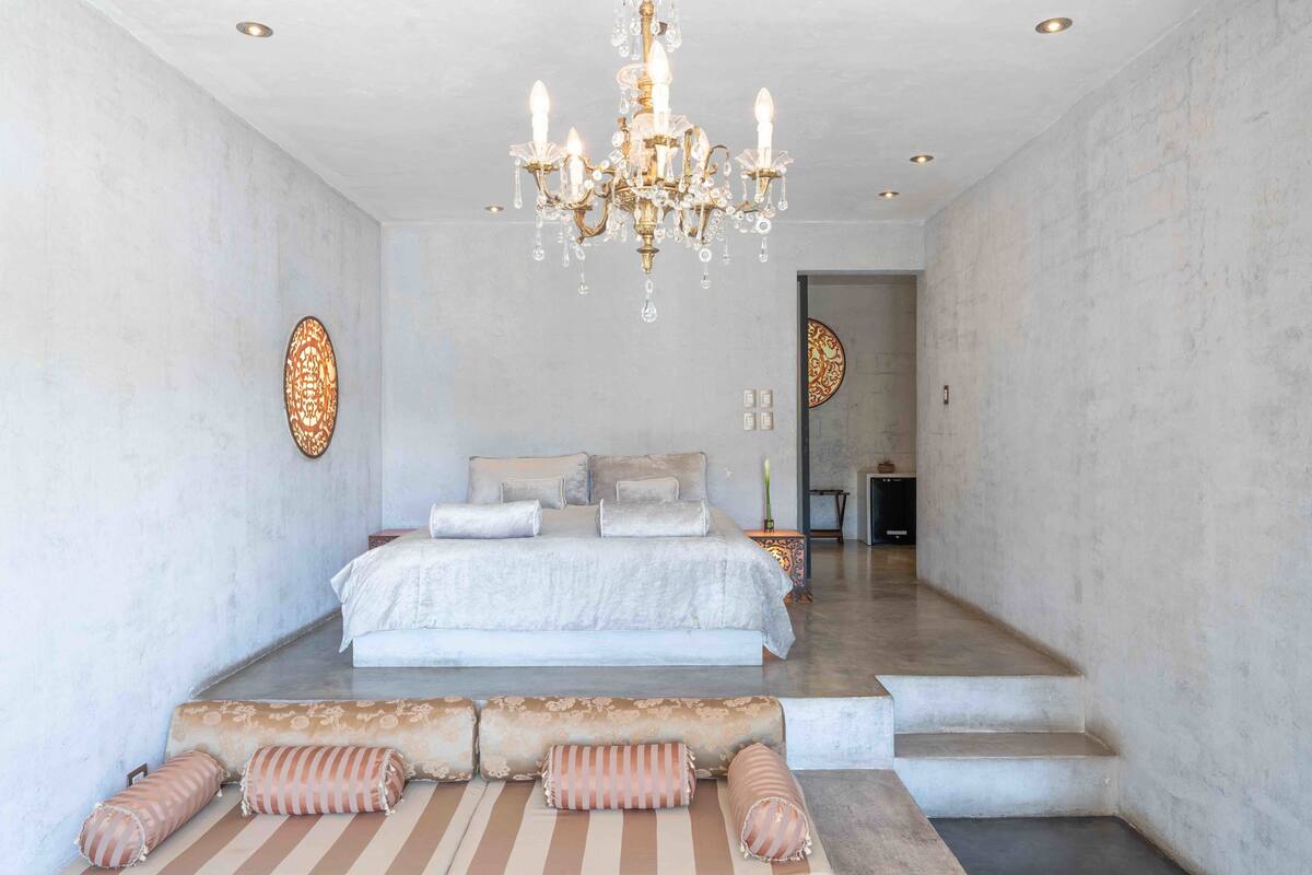 Ein Schlafzimmer mit einem großen Bett, einer Lüster und Blick auf einen Flur.