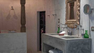 Un baño con un lavamanos grande de mármol, un espejo y un pilar de madera.