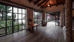 A spacious room with large windows, a wooden ceiling, and a stone pillar. - Casa Prana Hotel In Atitlan (Santa Cruz La Laguna)