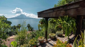 A wooden deck with potted plants and a view of a lake and a mountain. - Casa Prana Hotel In Atitlan (Santa Cruz La Laguna)