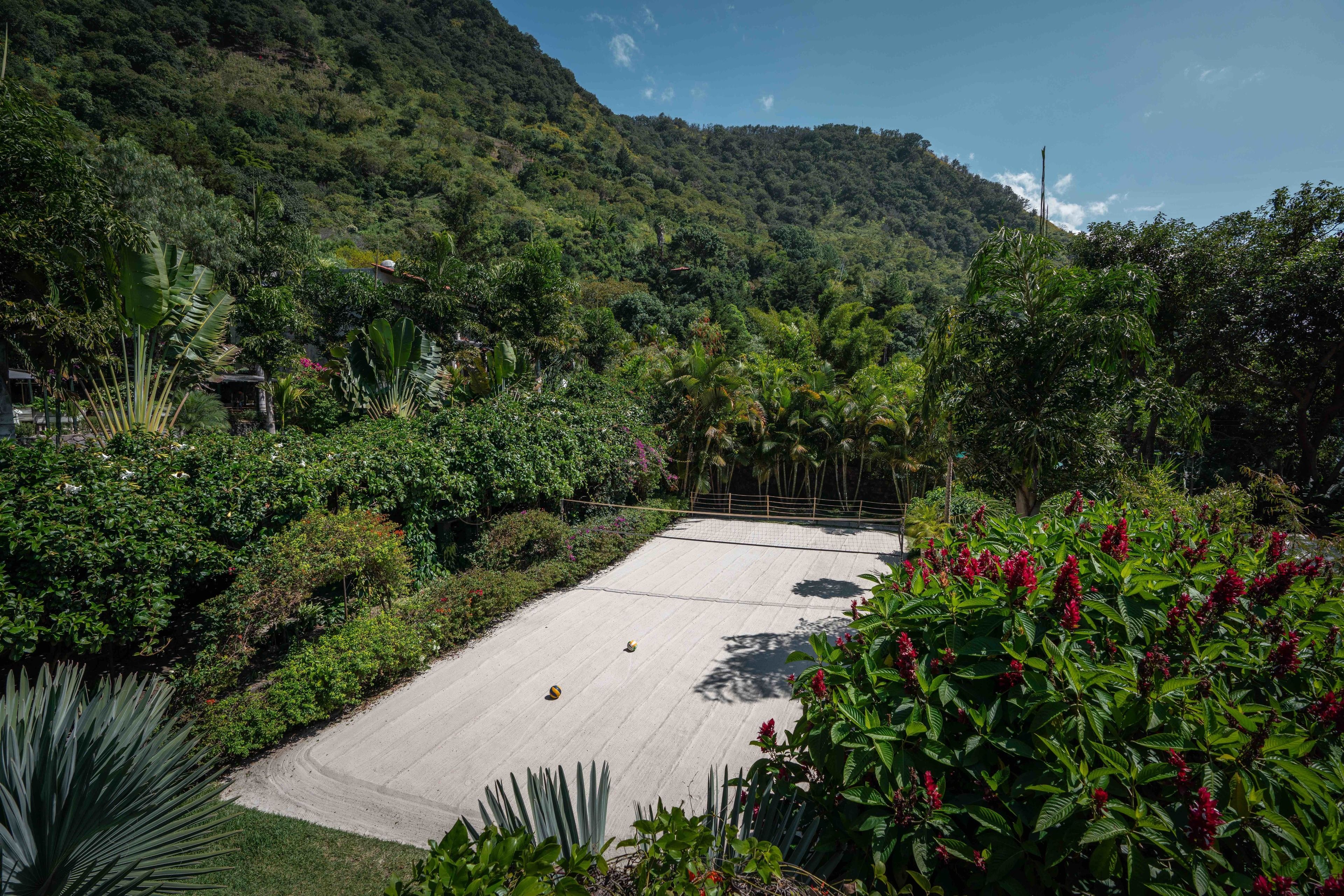 Una cancha de tenis rodeada de exuberante vegetación y colinas.