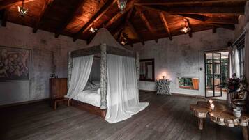 Un dormitorio rústico con cama con dosel, vigas de madera y un ventanal con vistas.