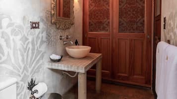 A bathroom with a wooden vanity, a large mirror, a chandelier, and a decorative wall.
