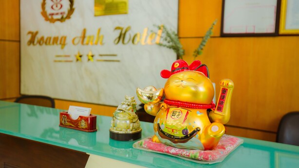 A reception desk with a gold plaque, a small red statue, and a golden figurine. - Hoang Anh 1 Hotel (Hanoi)
