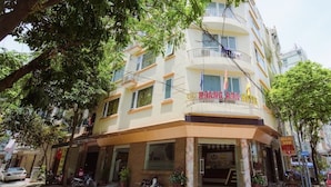 A hotel with a corner entrance, multiple balconies, and a sign indicating it is the Hoang Anh Hotel. - Hoang Anh 1 Hotel (Hanoi)