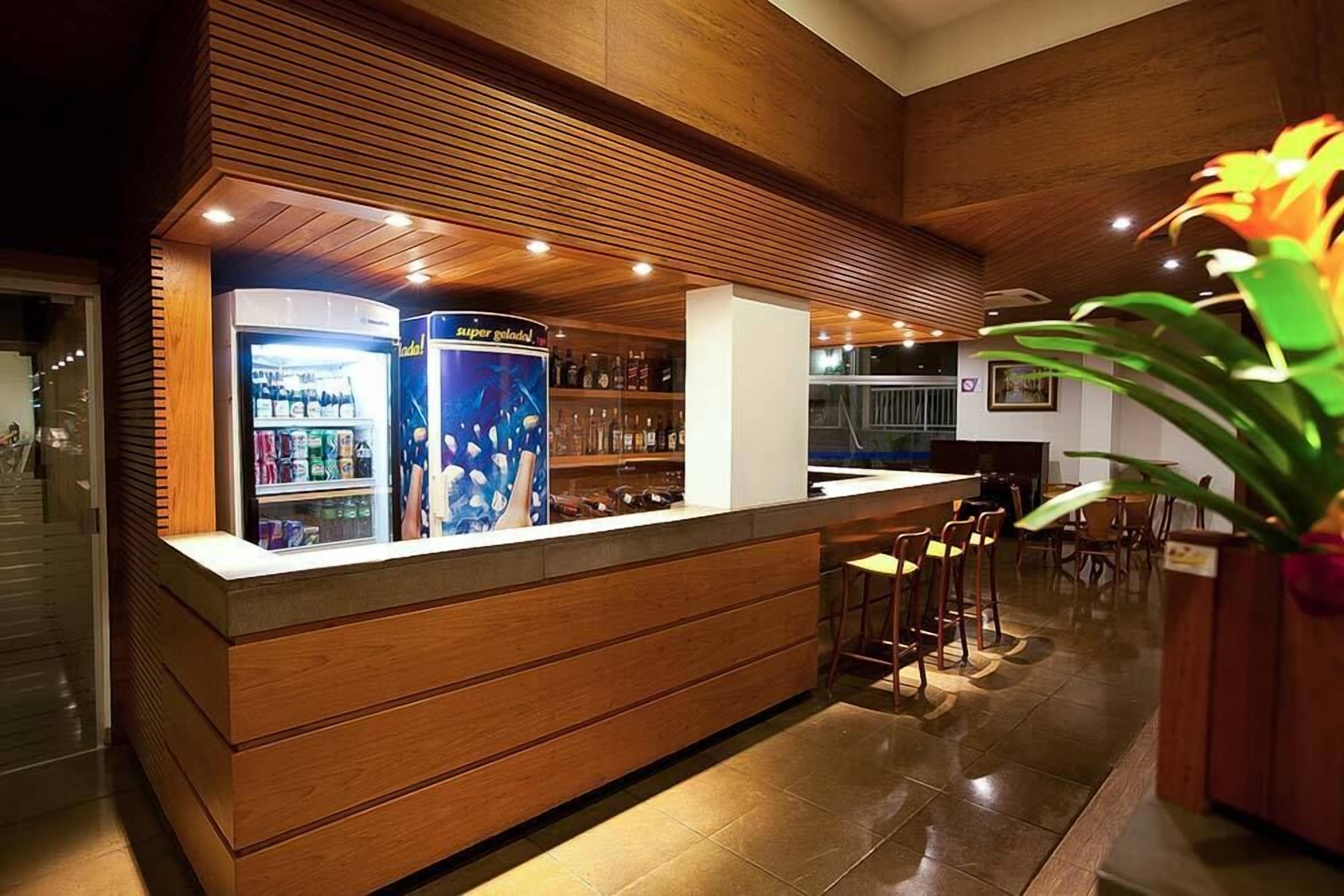 Un espace bar avec des panneaux de bois, un réfrigérateur-vitrine et des tabourets de bar.
