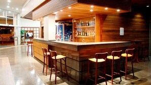Una zona de bar con mostrador de madera y taburetes, suelo de baldosas y un diseño interior moderno.