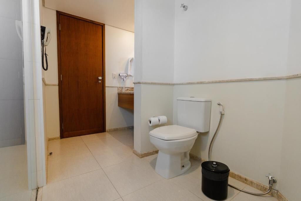 A small bathroom with a toilet, a shower, and a wooden door.