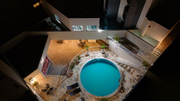 Una piscina interior de diseño circular, rodeada de zonas de estar y macetas con plantas.