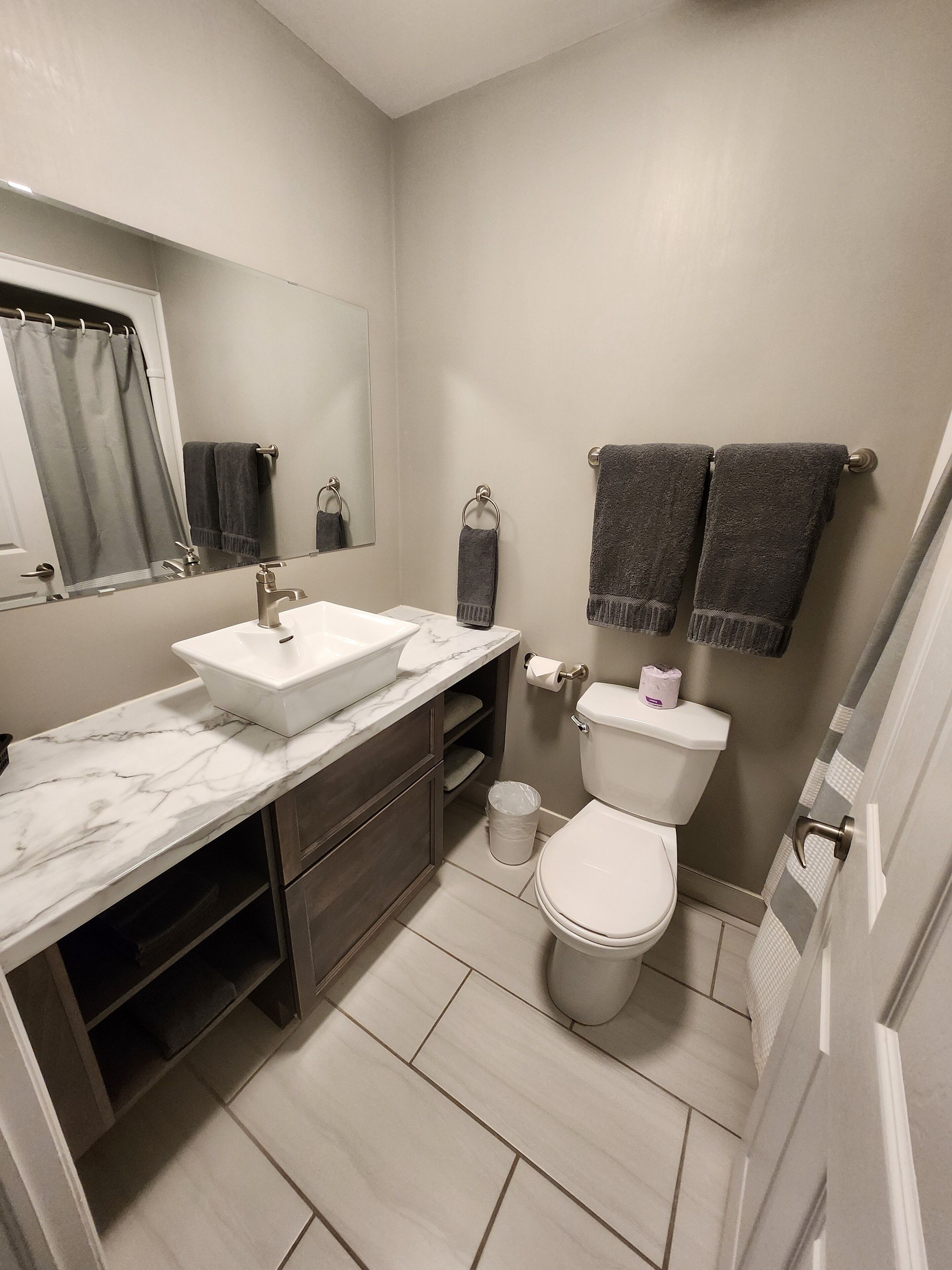 A modern bathroom with a marble sink, a toilet, and a shower area.