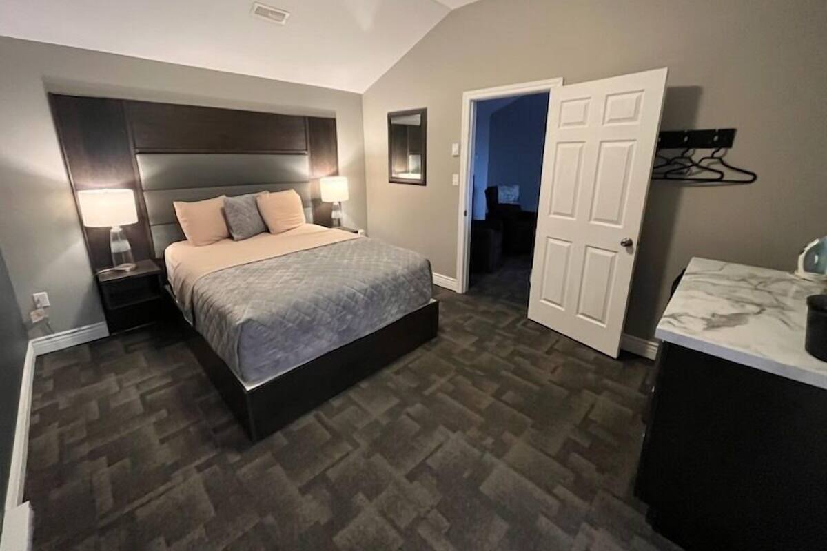 Un dormitorio con cama, mesitas de noche, cómoda y armario vestidor.