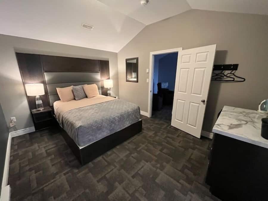 A bedroom with a bed, bedside tables, a nightstand, a dresser, and a walk-in closet.