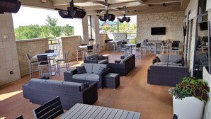 An outdoor patio area with wicker furniture, tables, and chairs. - Hilton Garden Inn Madison Sun Prairie (Sun Prairie)