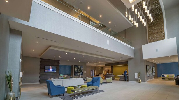 A spacious lobby with a high ceiling, a reception desk, seating area, and a TV screen. - Hilton Garden Inn Madison Sun Prairie (Sun Prairie)