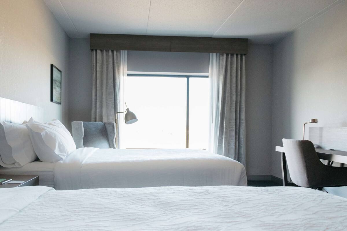 A hotel room with a large bed, a desk, and a chair.