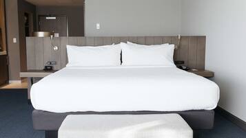 A modern hotel room with a large bed, bedside tables, a desk, and a wardrobe.