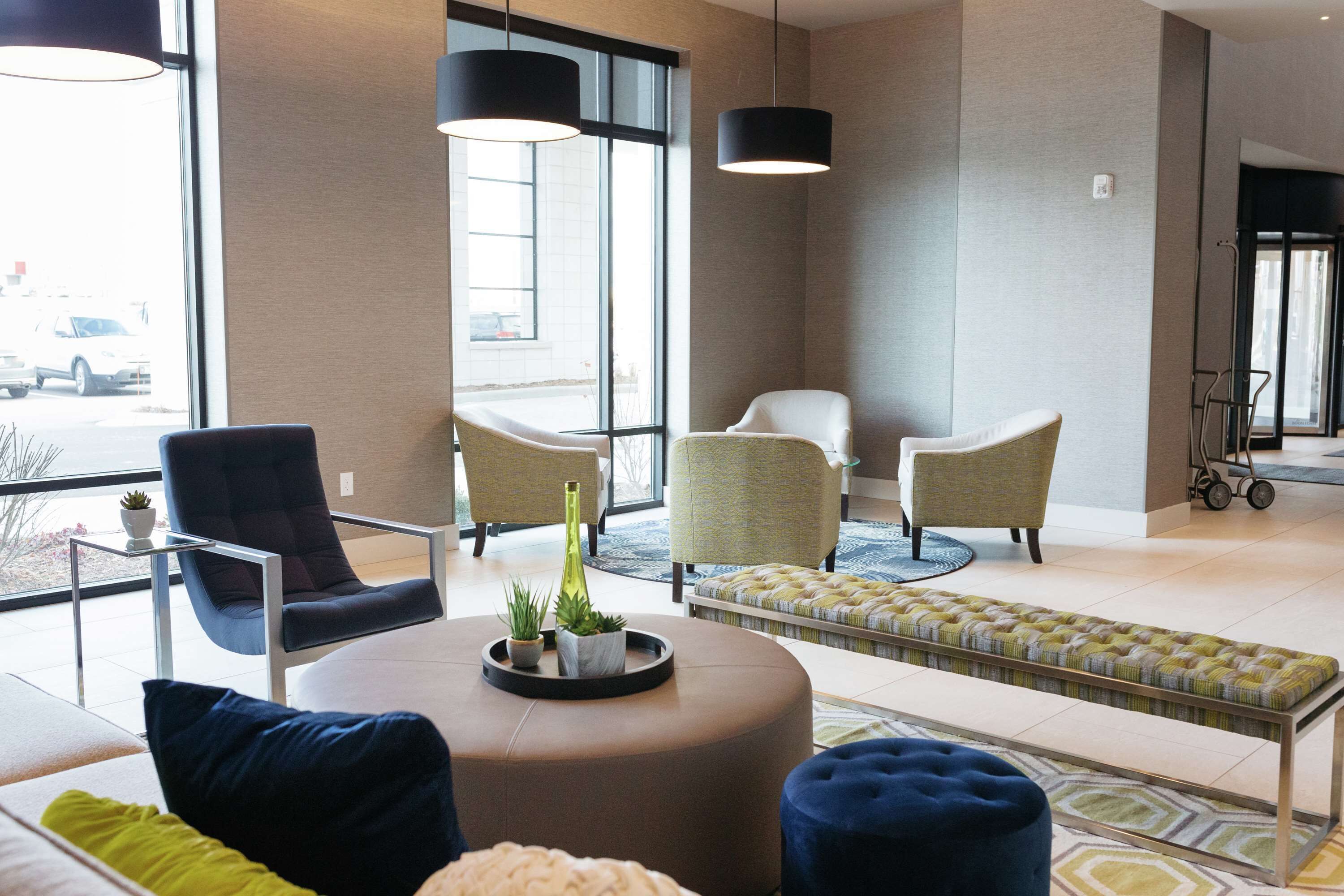A modern lobby with a seating area, large windows, and a view of the outside.