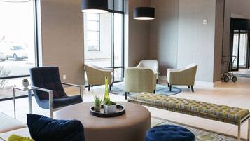 A modern lobby with a seating area, large windows, and a view of the outside.