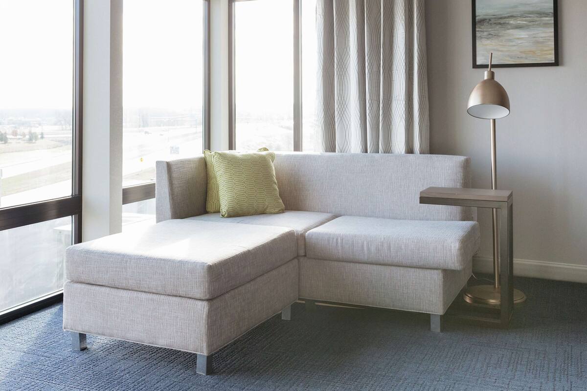 A modern living room with a sectional sofa, a small side table, and a floor lamp.