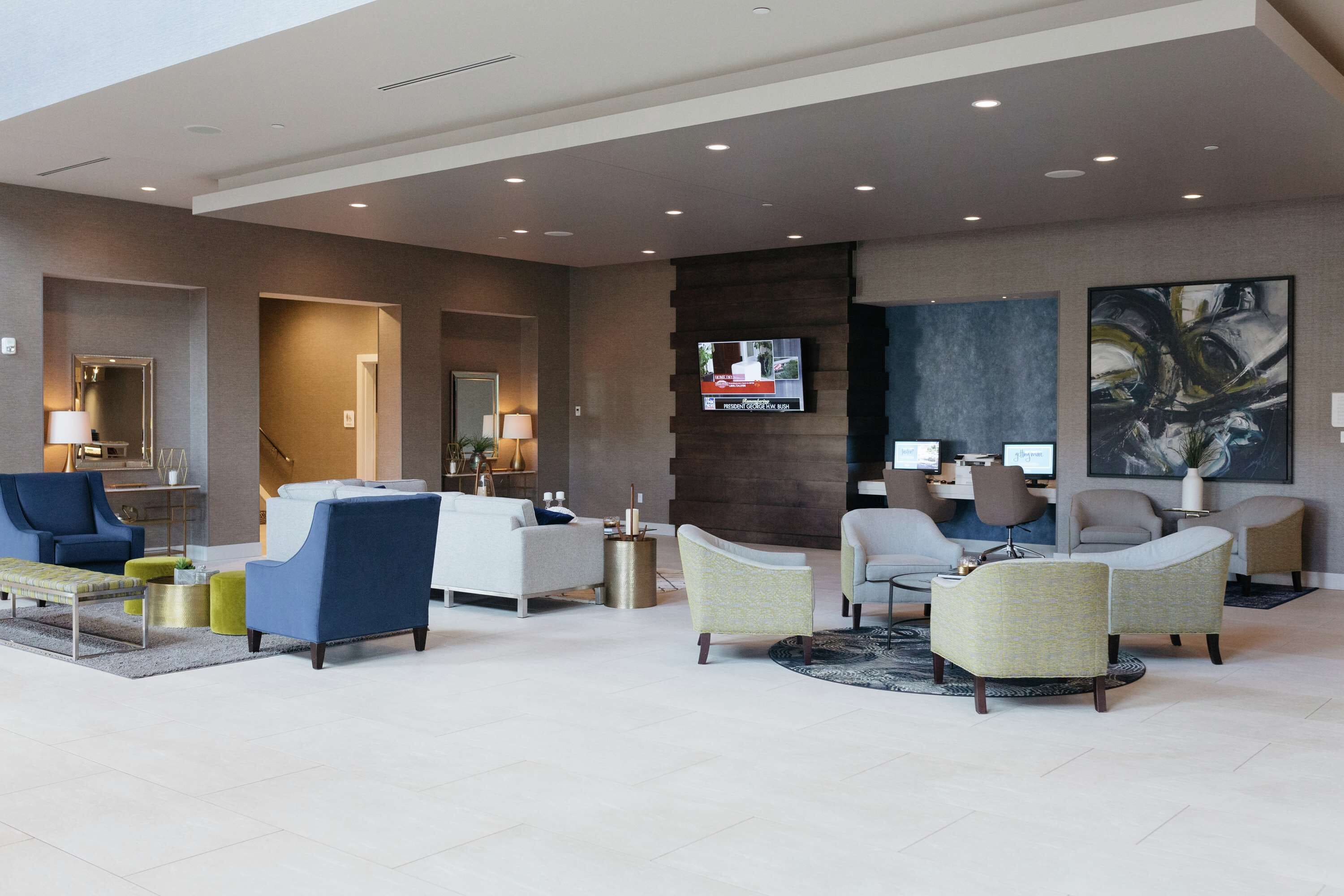 A modern lobby with seating areas, a reception desk, and a TV screen.