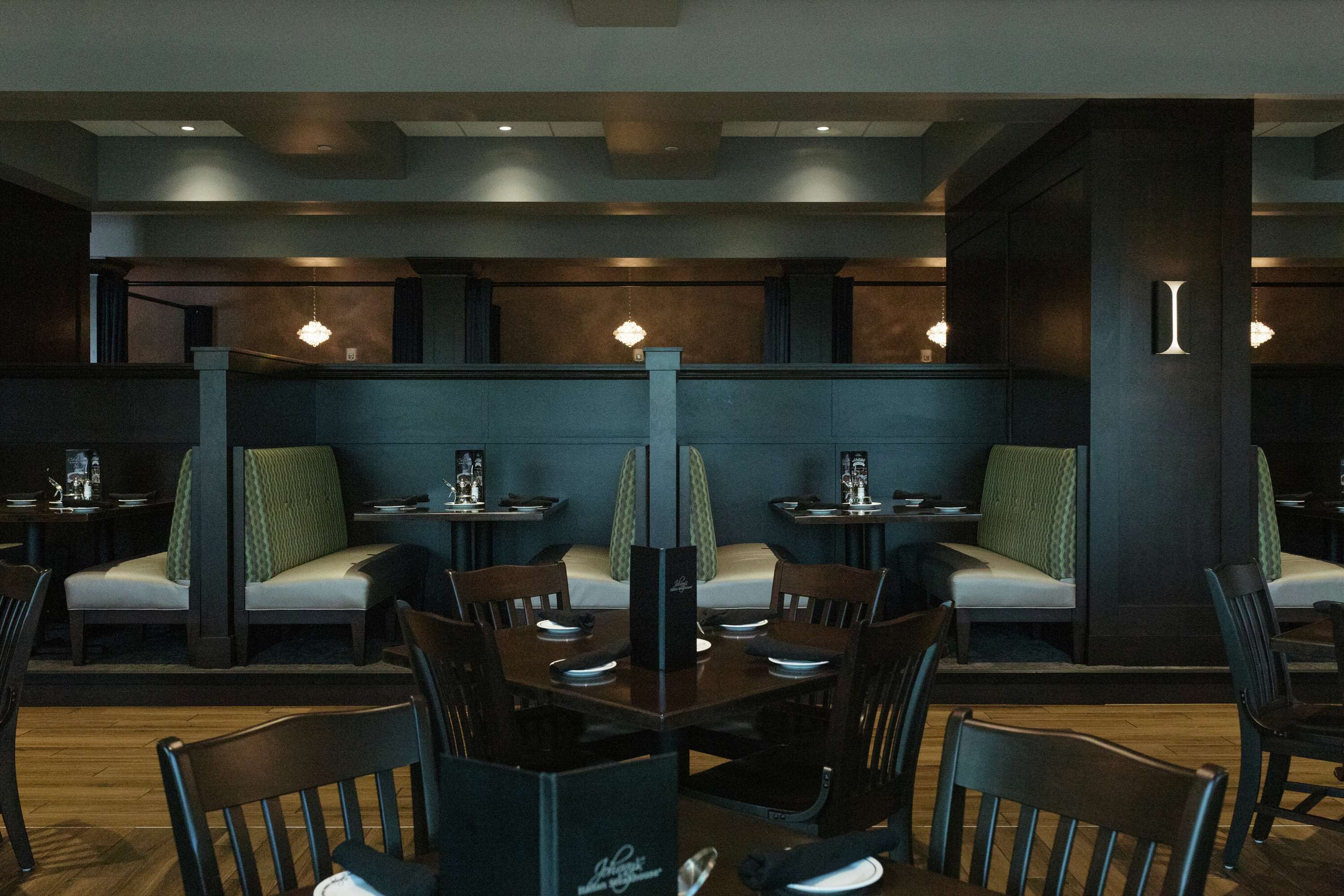 Un restaurant avec des banquettes et des tables, un plancher en bois et des luminaires suspendus.