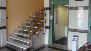 A staircase with marble steps and wooden handrails, leading to an elevator. - Hostal Serpol (Palencia)