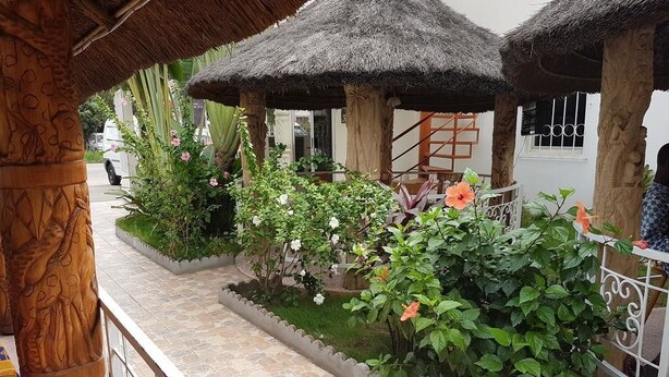 A garden area with thatched-roof structures, potted plants, and a tiled pathway.