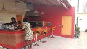 A restaurant with a red and brown color scheme, featuring a counter with stools and a kitchen area with appliances.