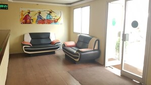 A lobby with two sofas, a wall painting, and a door leading outside.