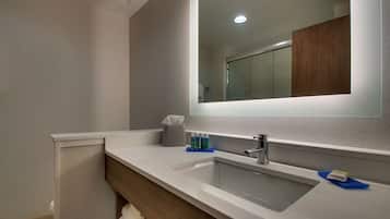 A modern bathroom with a large mirror, a sink, and a towel rack.