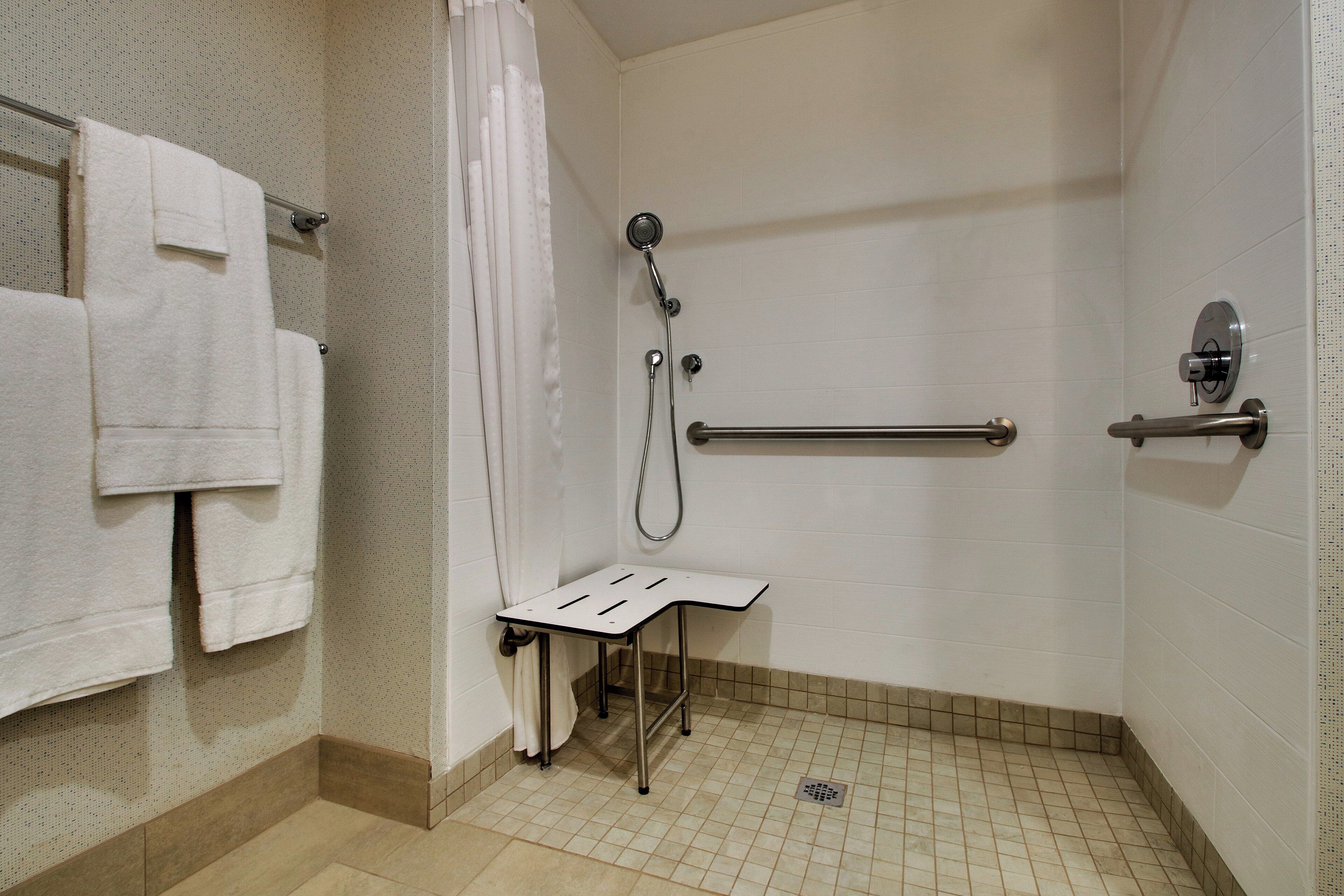 A shower area with a grab bar, a towel rack, and a showerhead.