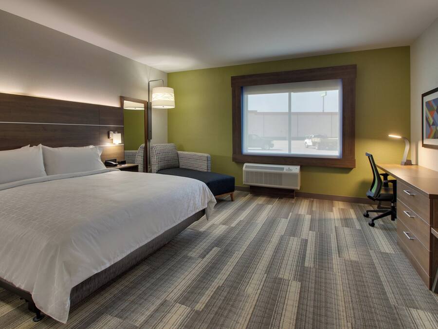 Une chambre d’hôtel avec un grand lit, un bureau, une chaise, une fenêtre et un téléviseur.