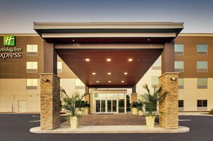 Edificio de Holiday Inn Express con entrada techada, pilares de piedra y plantas en macetas.