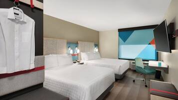 A hotel room with two beds, a desk, a chair, a TV, and a wardrobe.