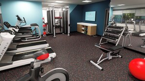 Ein Fitnessstudio mit Laufbändern, Kraftgeräten und einem Spiegel.