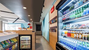 Un área moderna y limpia para alimentos y bebidas, con bebidas refrigeradas, aperitivos y una variedad de productos envasados.
