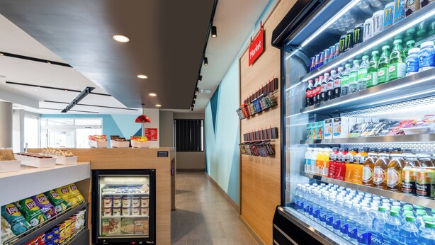 A clean, modern food and beverage area with refrigerated drinks, snacks, and a variety of packaged goods.
