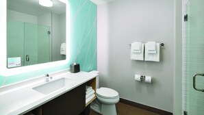 Un baño moderno con un espejo grande, un lavabo blanco y un inodoro.