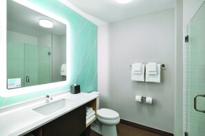 Une salle de bain moderne avec un grand miroir, un lavabo blanc et des toilettes.