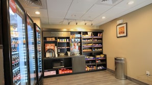 A self-service beverage kiosk with refrigerated drink dispensers and shelves stocked with snacks and beverages. - Candlewood Suites Memphis East by IHG (Memphis)